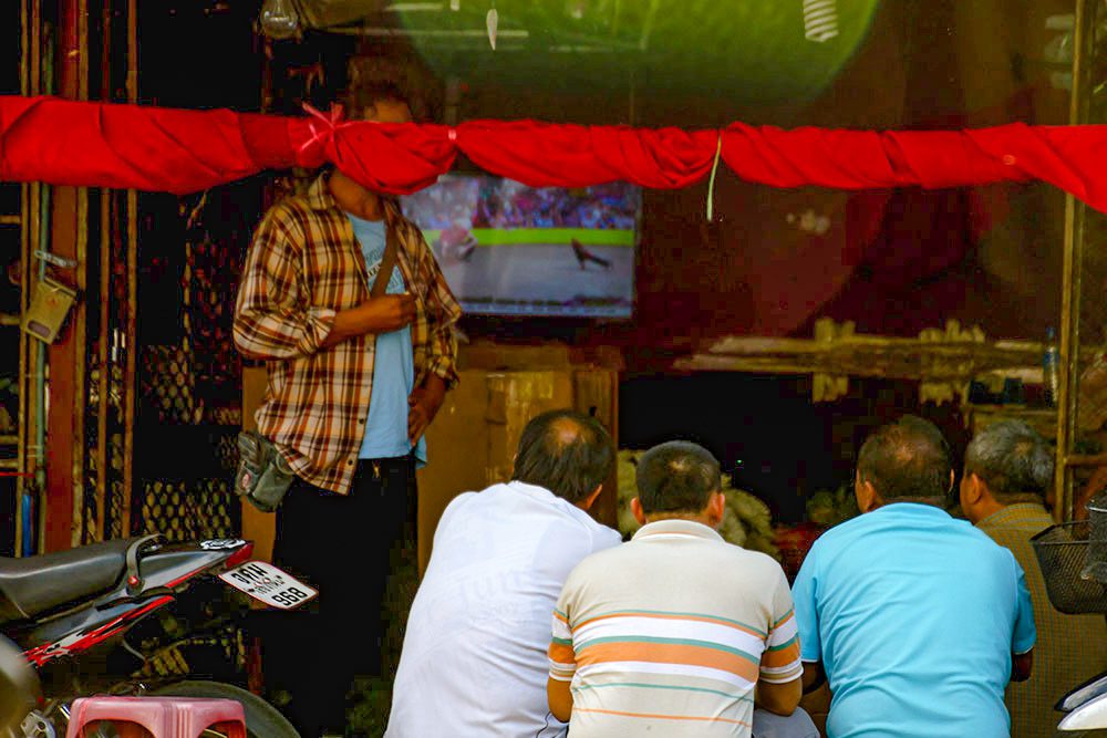 A group of men watching cockfights on television and betting on the outcome